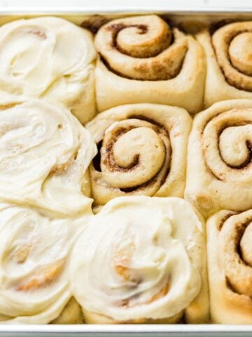 Classic cinnamon rolls in a pan with thick cream cheese frosting spread over the tops
