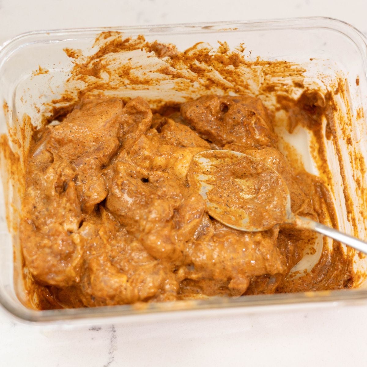 Chicken thighs marinating in yogurt, garam masala, lemon juice, and Kashmiri chili powder