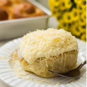 Close-up of soft Filipino ensaymada with frosting and grated cheese topping