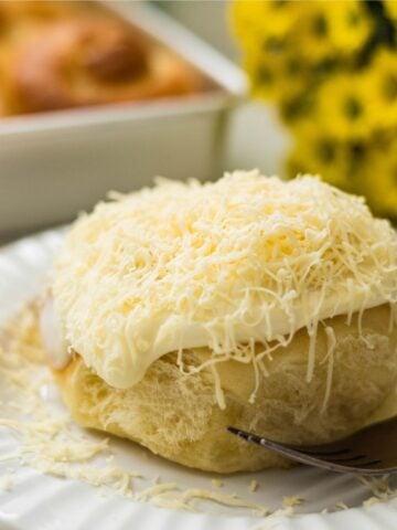 Close-up of soft Filipino ensaymada with frosting and grated cheese topping
