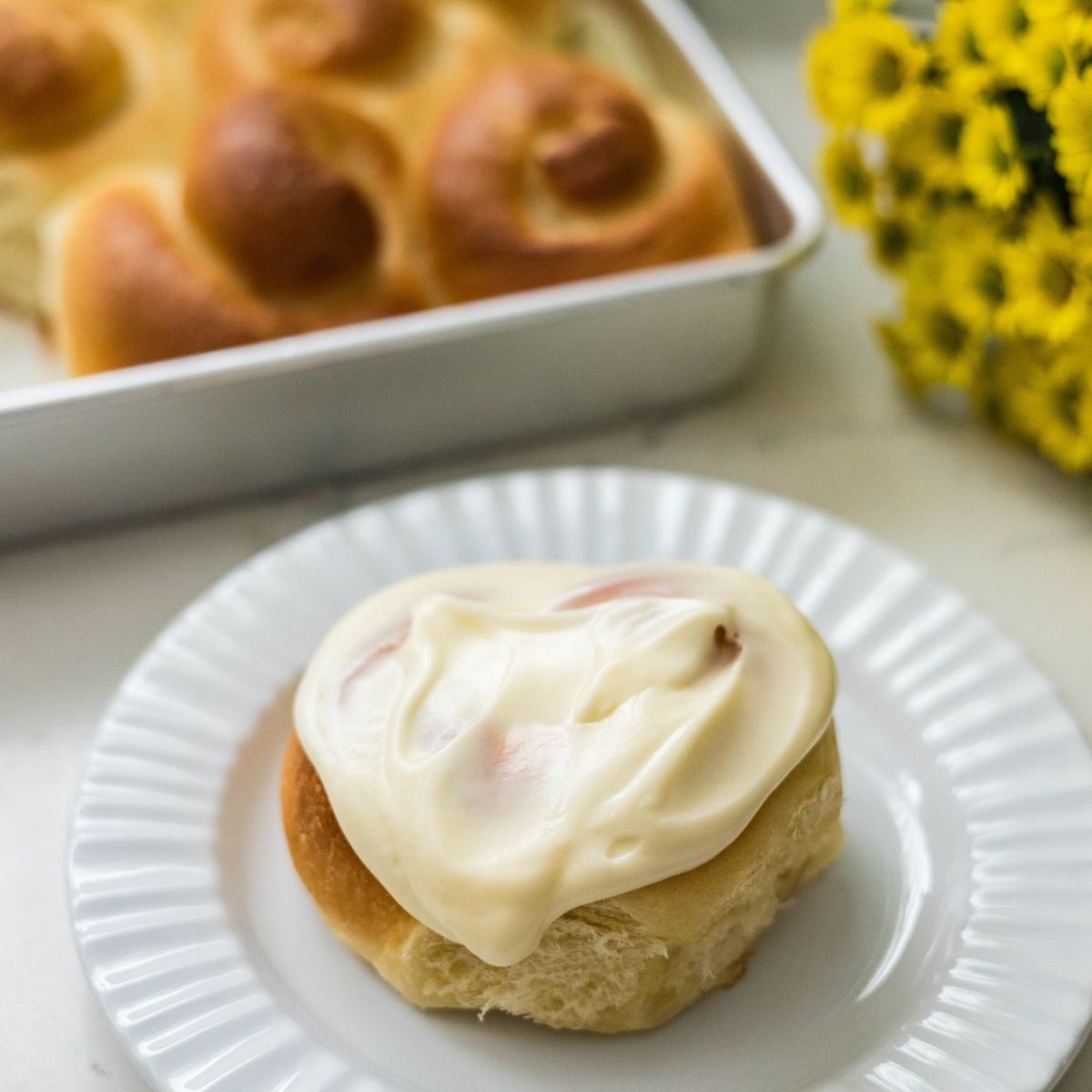 Freshly baked Filipino ensaymada covered with thick cream cheese frosting