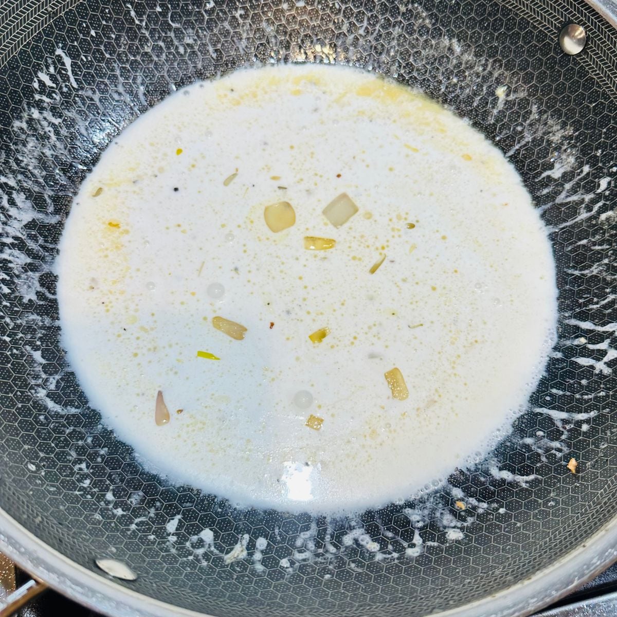 Creamy coconut milk sauce with garlic and aromatics simmering in a pan for ginataang salmon