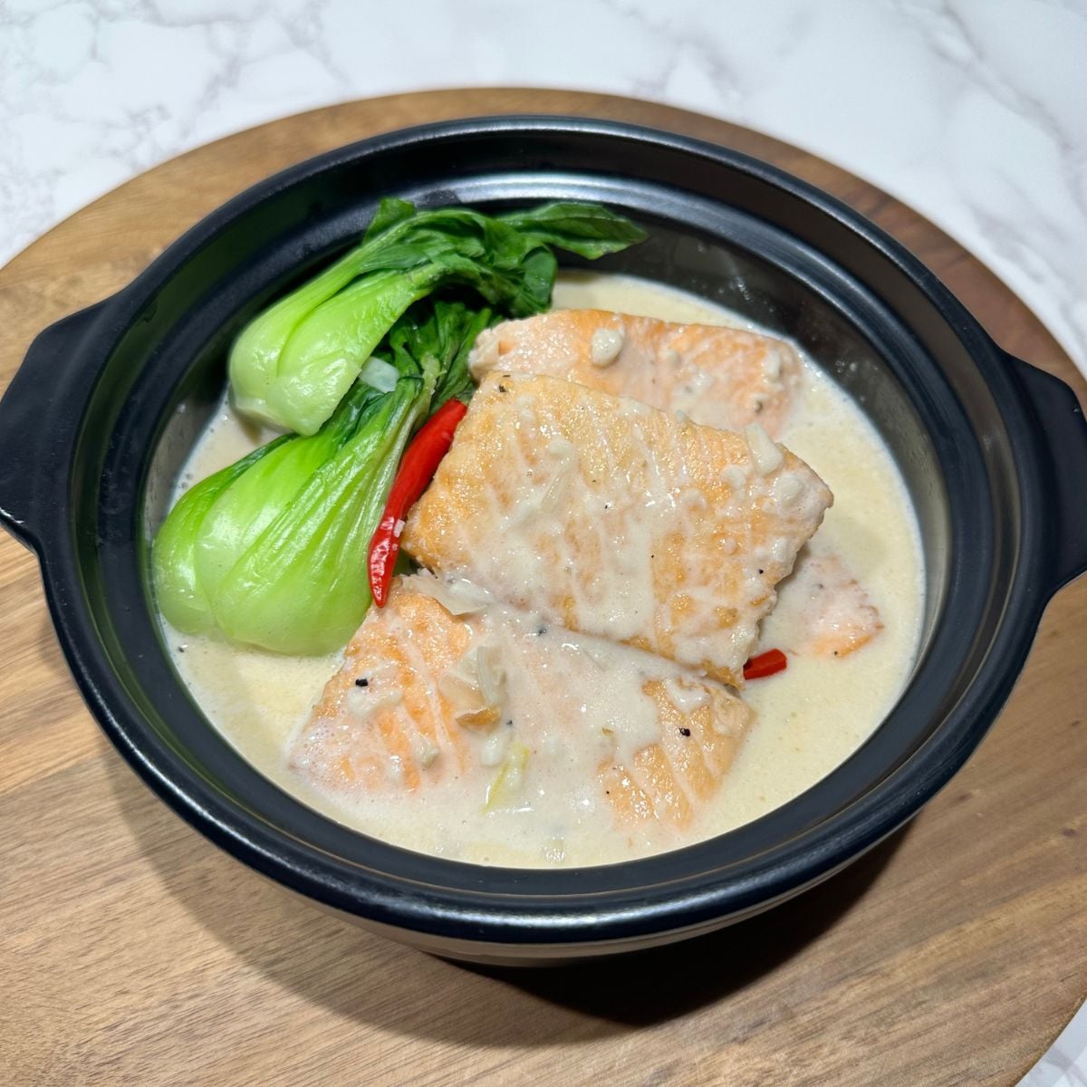 Ginataang salmon served in a bowl with bok choy and creamy coconut milk sauce