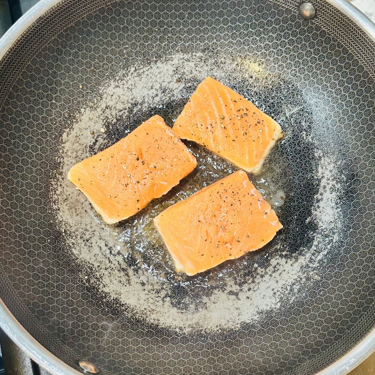 Salmon fillets shallow frying in a pan before being added to ginataang salmon coconut milk sauce