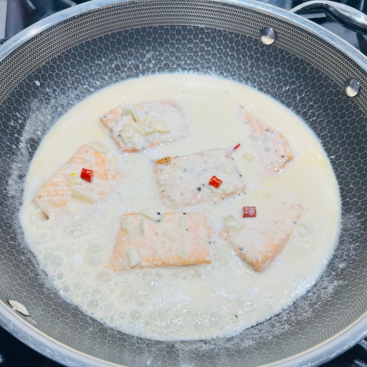 Ginataang salmon simmering in creamy coconut milk with chopped aromatics and red chili