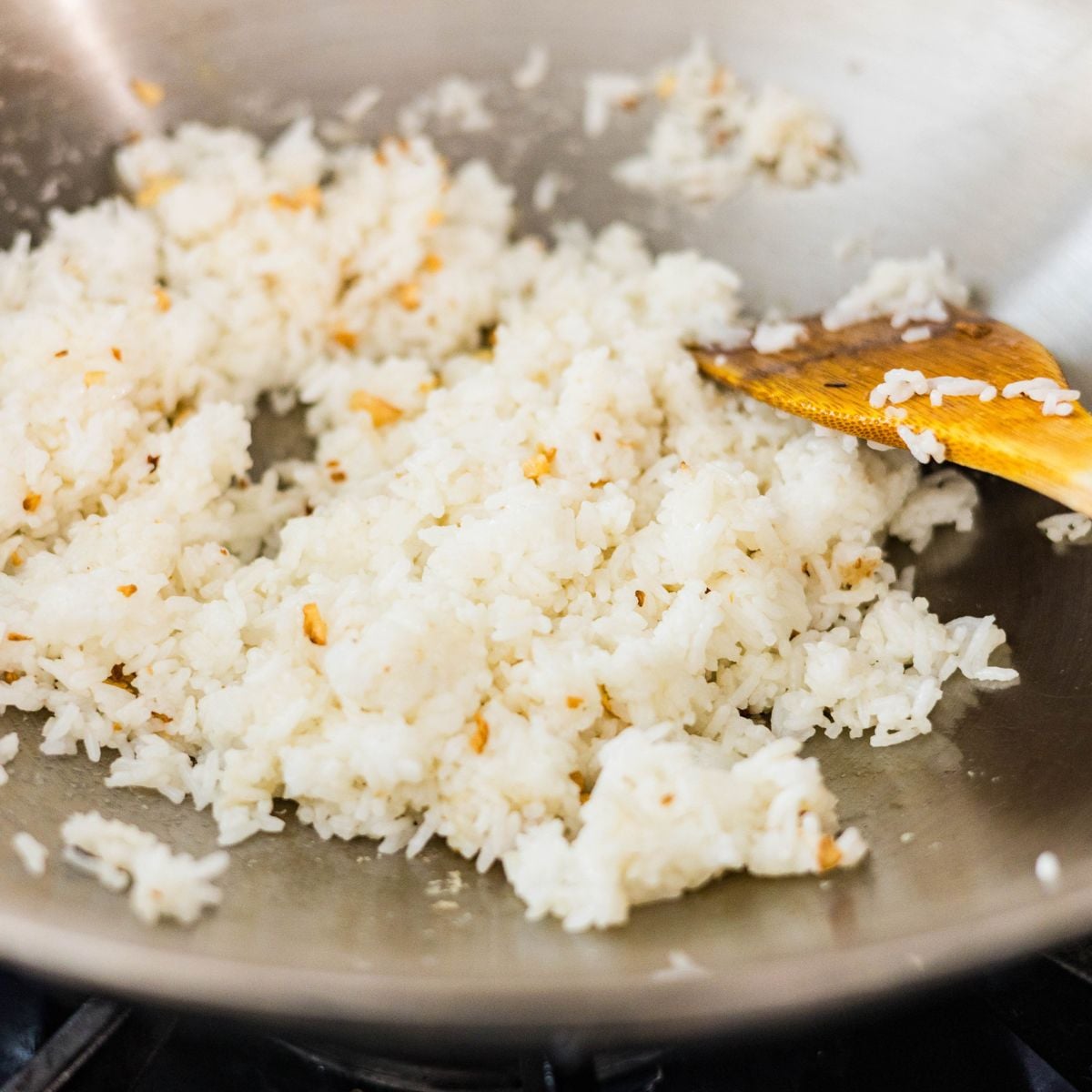 Garlic fried rice cooking in a wok with toasted garlic for Filipino sinangag.