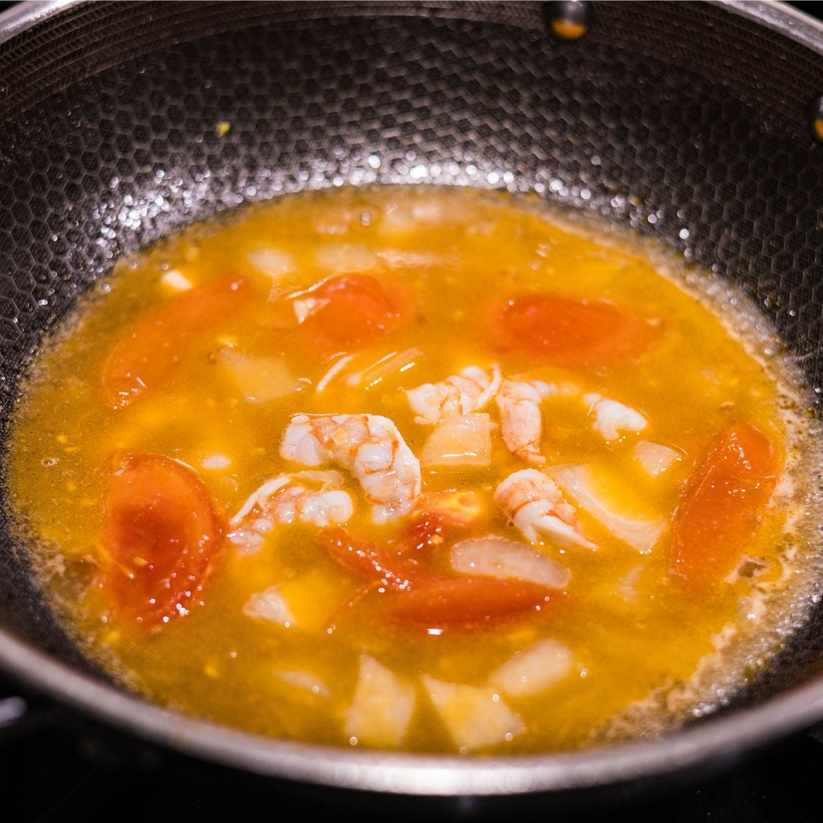 Ginisang sayote with shrimp simmering in broth with tomatoes, onion, and seasonings.