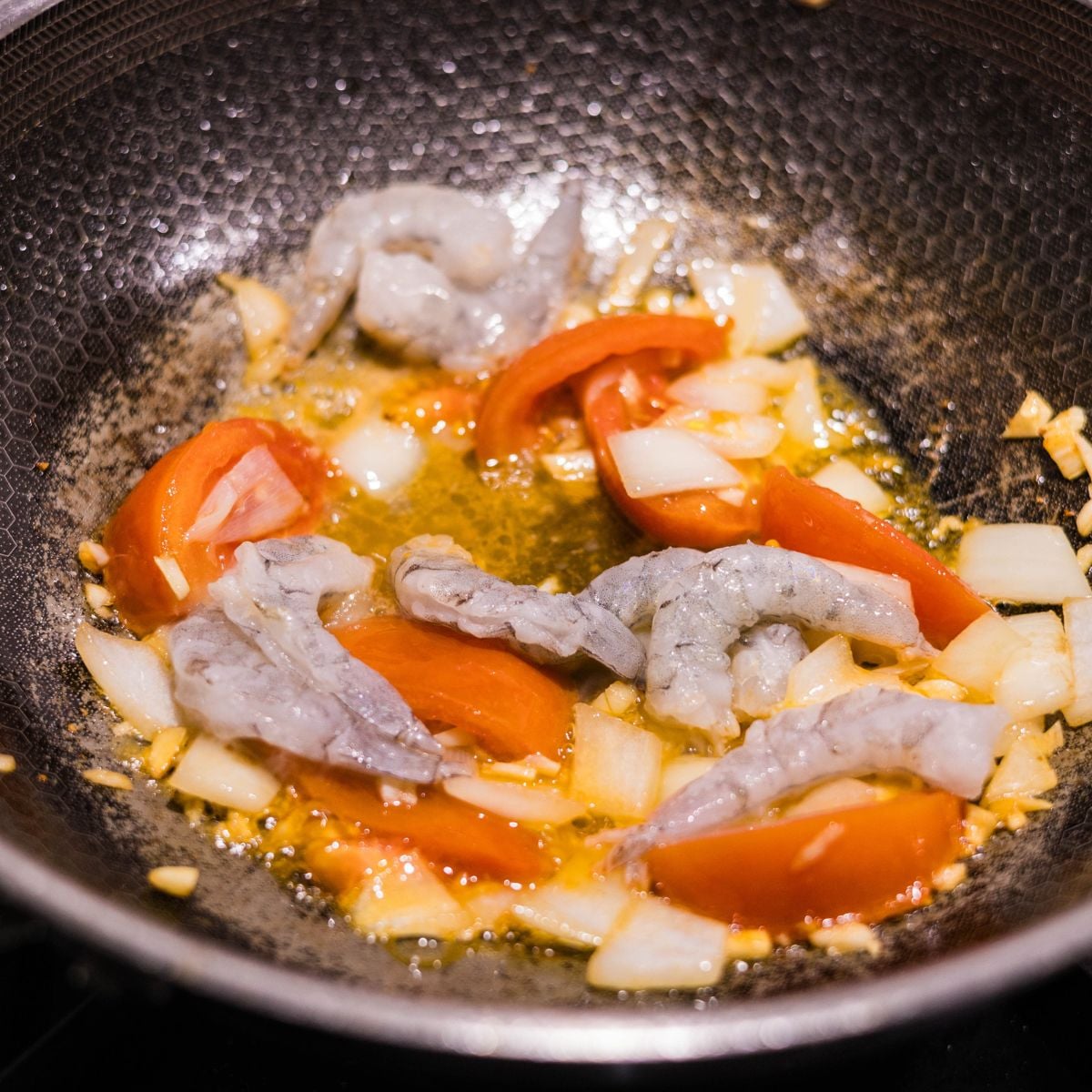 Raw shrimp added to sautéed garlic, onion, and tomatoes for ginisang sayote with shrimp.