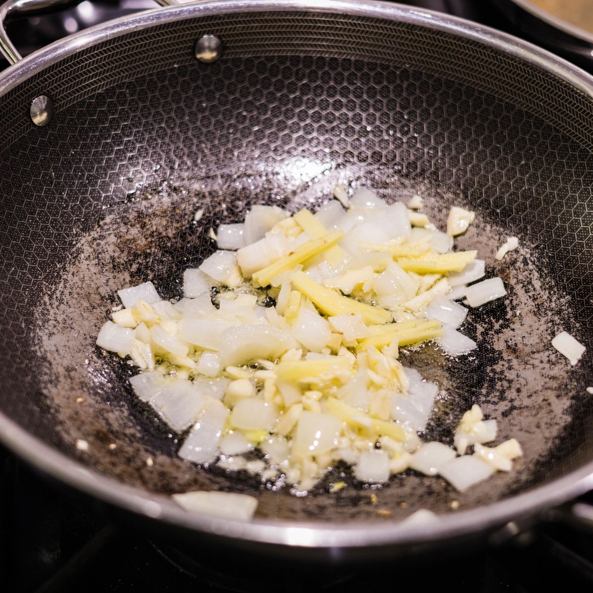 Garlic, ginger, and onion sautรฉing in oil in a skillet.