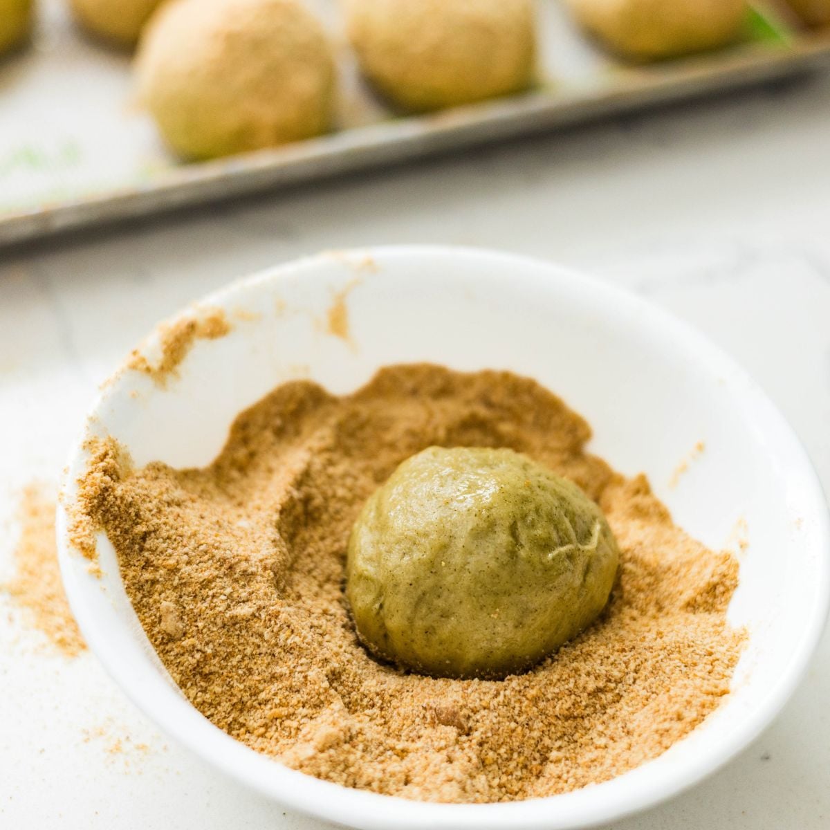 Breadcrumb-coated malunggay pandesal dough balls on a baking sheet before the second rise.