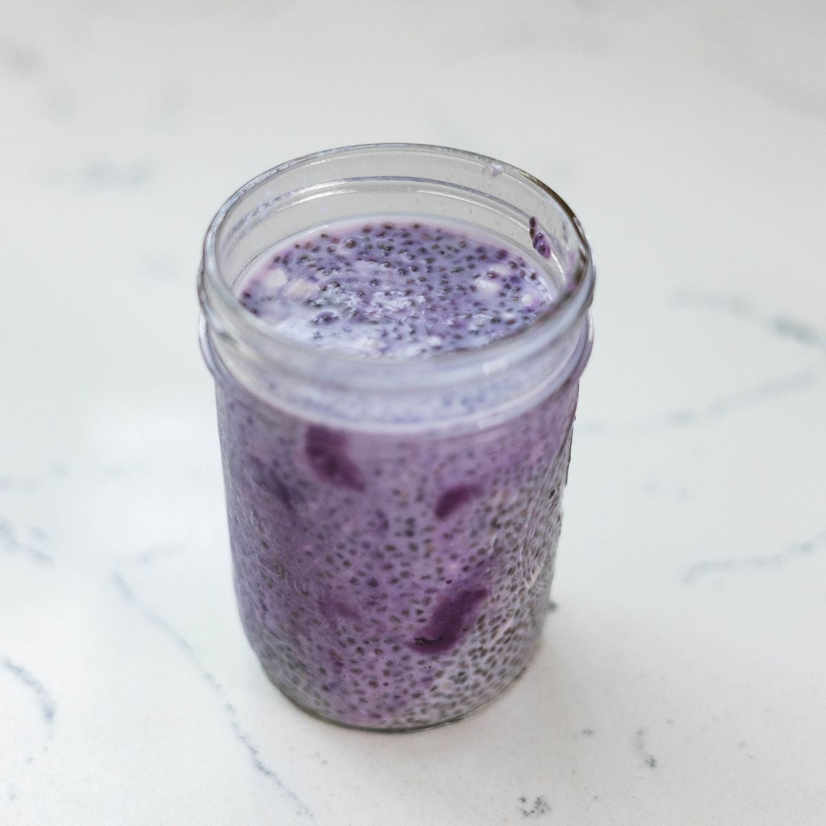 Ube chia pudding in a glass jar with visible chia seeds and pieces of ube halaya