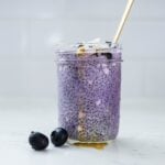 Ube chia pudding with blueberries, coconut flakes, and honey served in a glass jar