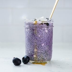 Ube chia pudding with blueberries, coconut flakes, and honey served in a glass jar