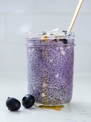 Ube chia pudding with blueberries, coconut flakes, and honey served in a glass jar