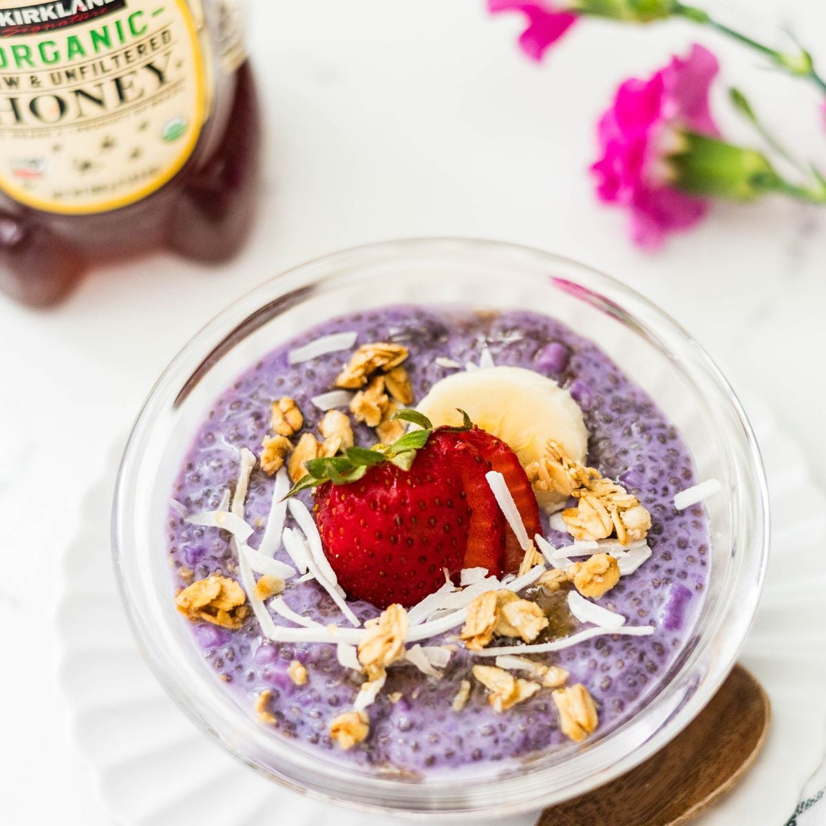 Ube chia pudding with strawberries, banana, coconut flakes, and honey served in a bowl