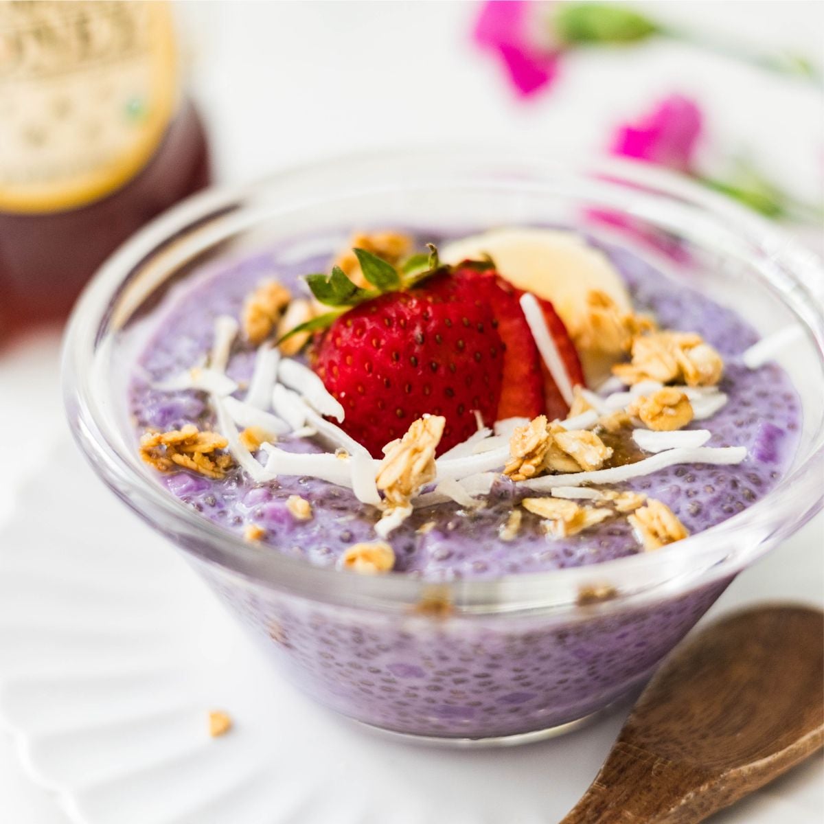 Ube chia pudding with strawberries, banana, coconut flakes, and honey served in a bowl