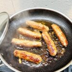 Vigan longganisa sausages cooking in a pan until golden brown and caramelized