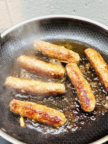 Vigan longganisa sausages cooking in a pan until golden brown and caramelized