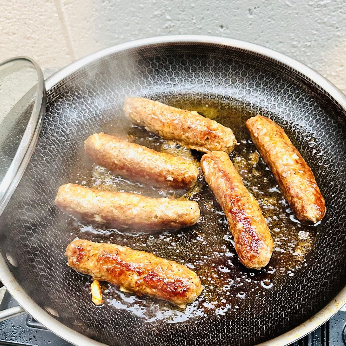 Vigan longganisa sausages cooking in a pan until golden brown and caramelized