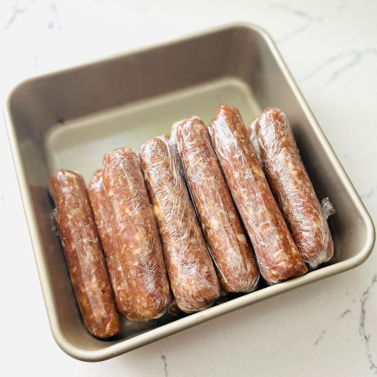 Freshly made Vigan longganisa neatly arranged in a container wrapped in plastic