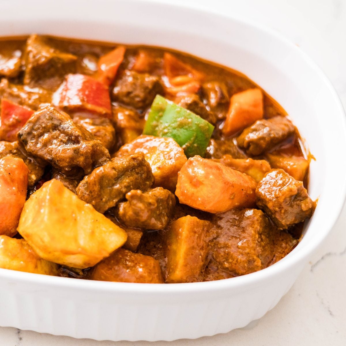 Filipino Beef Caldereta with Cheese served with potatoes, carrots, and bell peppers