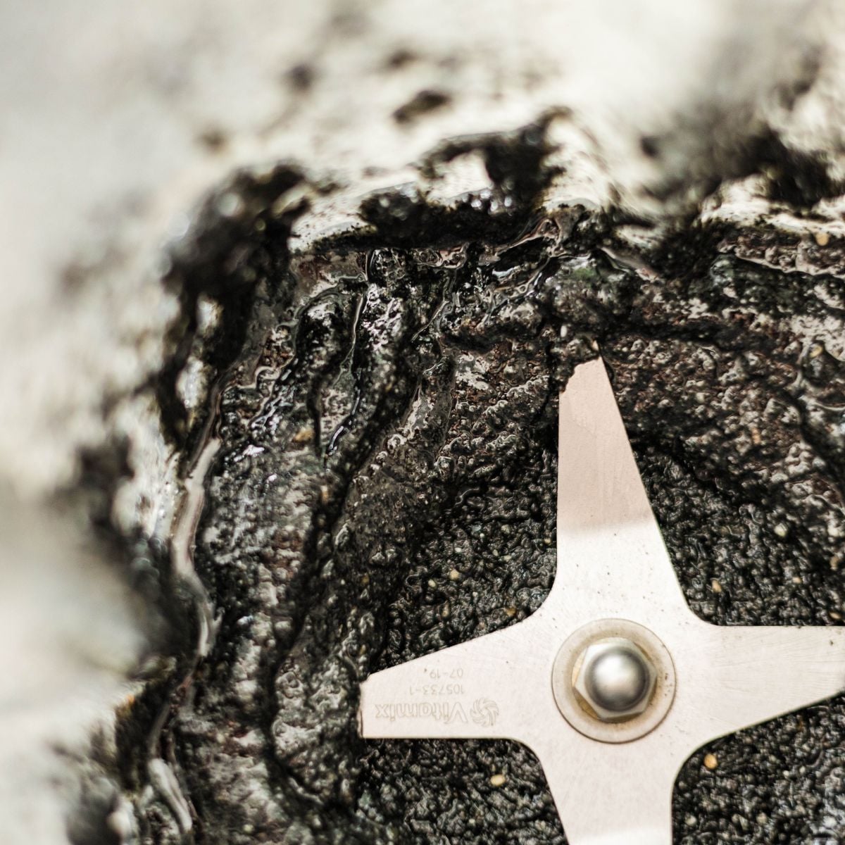 Close-up of thick black sesame paste inside a blender after grinding.