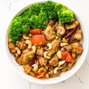 Close-up of cashew chicken with broccoli, red bell peppers, sesame seeds, and toasted cashews.