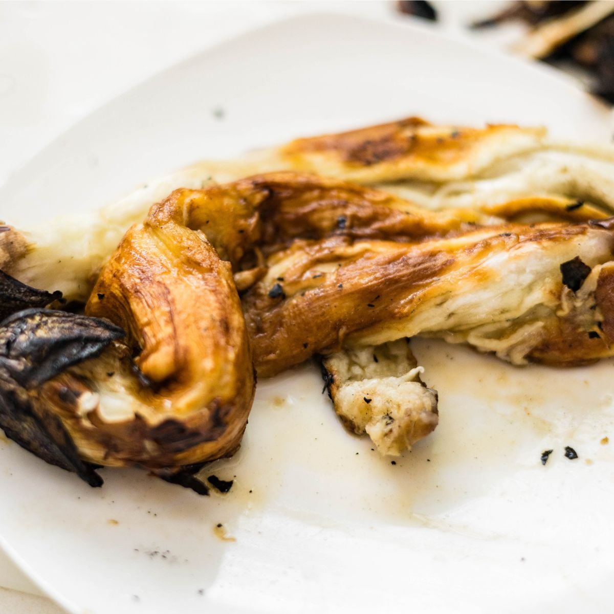 Peeled charred eggplants on a plate for Filipino eggplant salad.