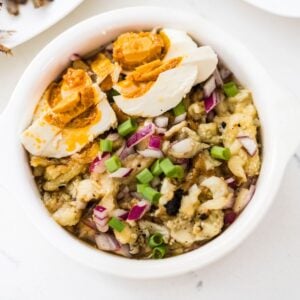 Filipino eggplant salad with salted egg, red onion, and green onions in a serving bowl.