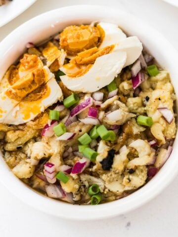 Filipino eggplant salad with salted egg, red onion, and green onions in a serving bowl.