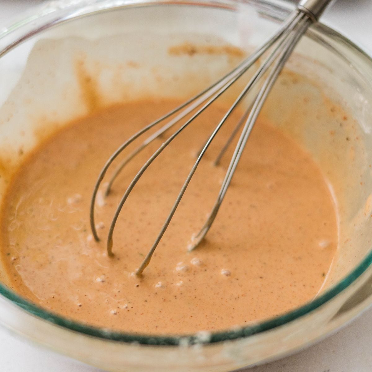 Seasoned okoy batter mixed in a glass bowl with a whisk.