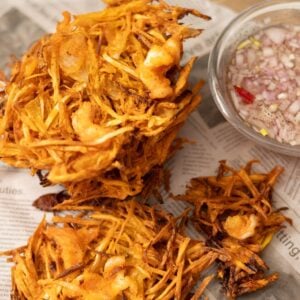 Stack of crispy okoy vegetable fritters with shrimp served with vinegar dipping sauce.