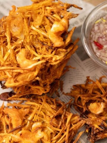 Stack of crispy okoy vegetable fritters with shrimp served with vinegar dipping sauce.