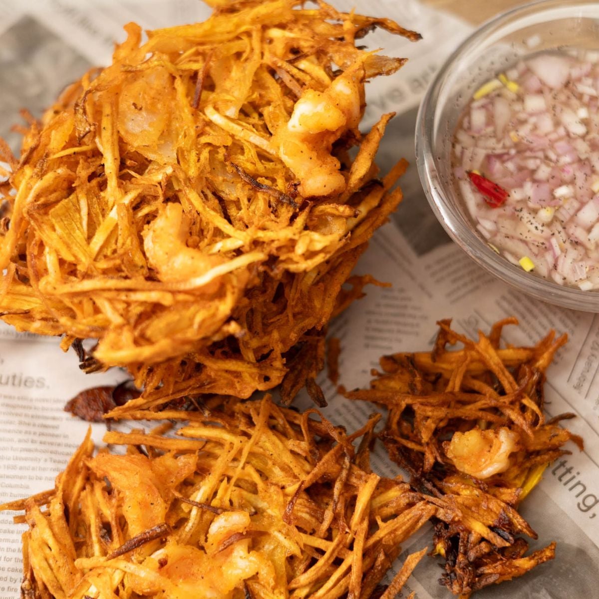 Stack of crispy okoy vegetable fritters with shrimp served with vinegar dipping sauce.
