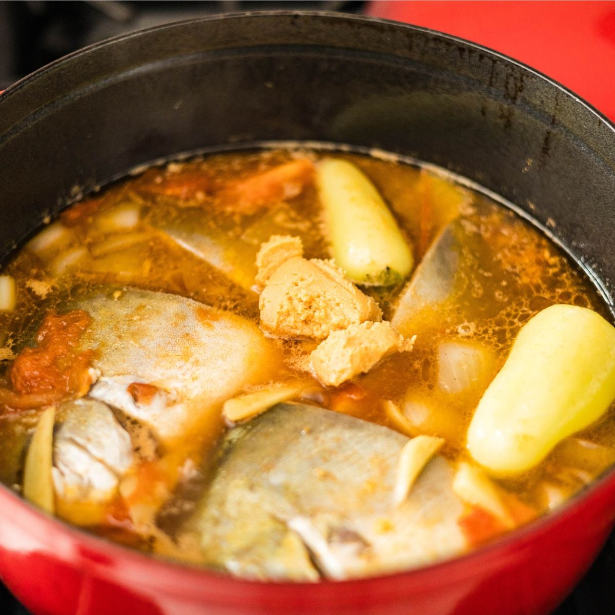 Fresh pompano fish pieces cooking in a tangy sinigang sa miso broth.