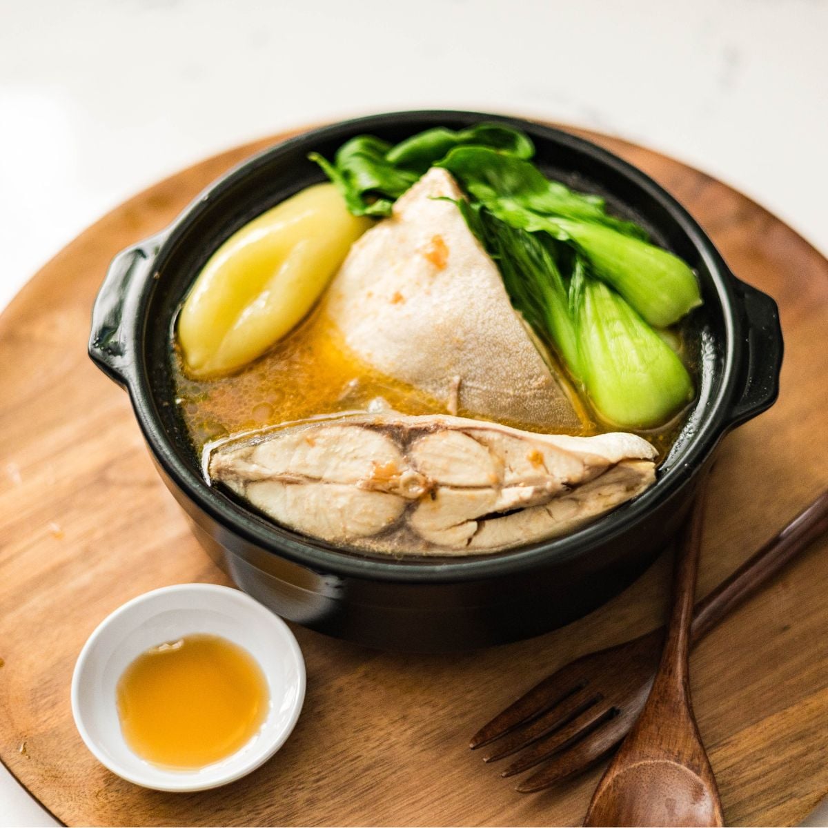 A bowl of sinigang sa miso with pompano, bok choy, tomatoes, and warm sour broth served with patis.