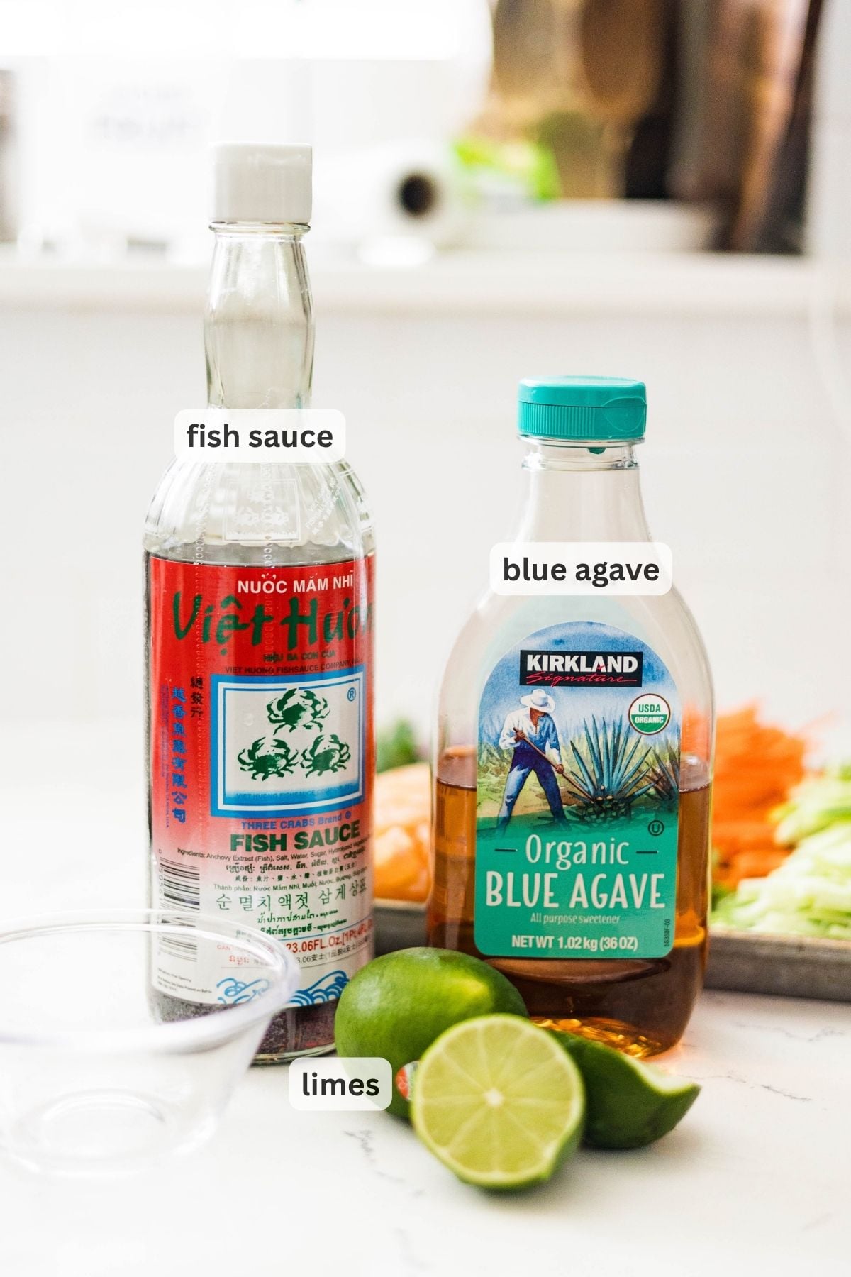 Fish sauce, blue agave, and limes on a counter for making pomelo salad dressing.