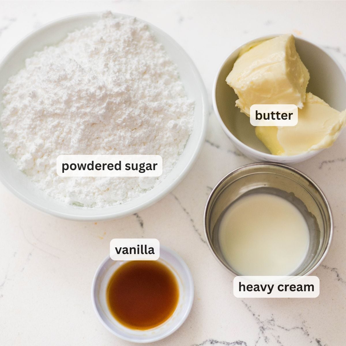 Powdered sugar, butter, heavy cream, and vanilla extract measured for vanilla buttercream frosting.