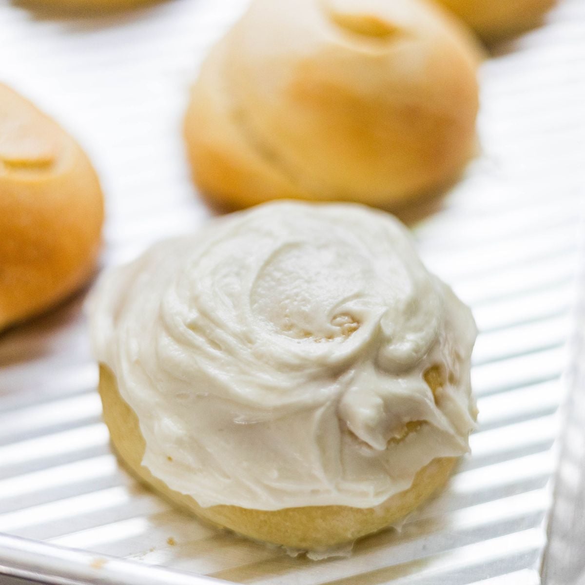 Soft baked bun topped with a thick swirl of creamy vanilla buttercream frosting.