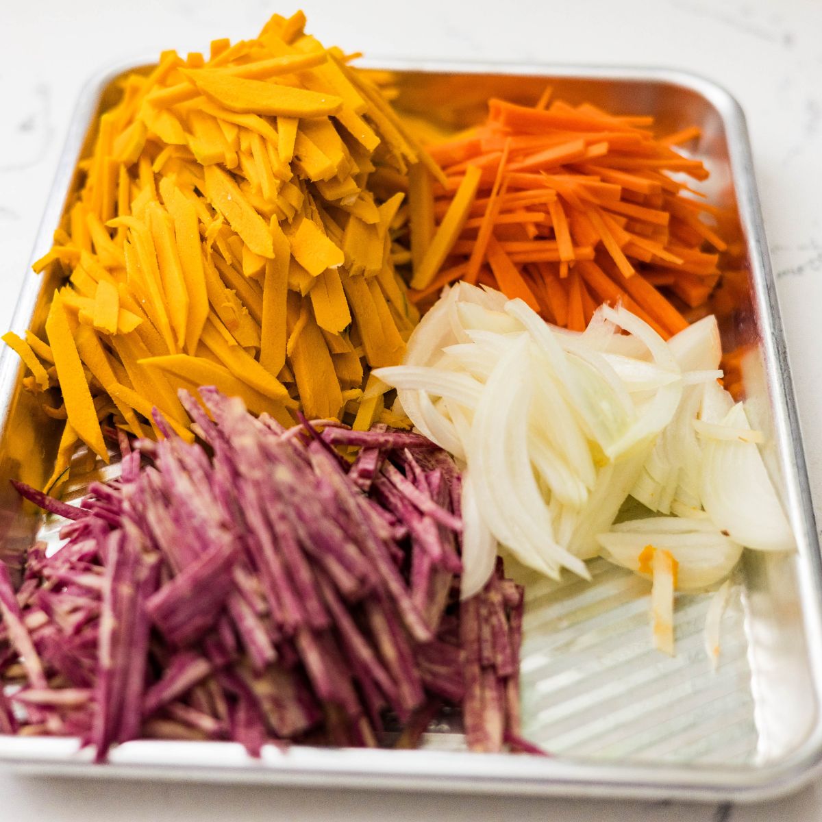 Julienned squash, carrots, onion, and purple sweet potato prepared for making okoy.