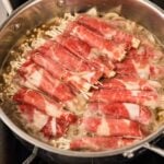 Enoki beef rolls simmering in dashi broth until the beef loses its pink color