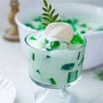 Creamy buko pandan salad served in a glass with pandan jelly and coconut