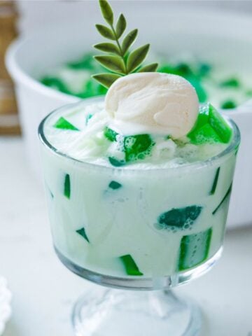 Creamy buko pandan salad served in a glass with pandan jelly and coconut