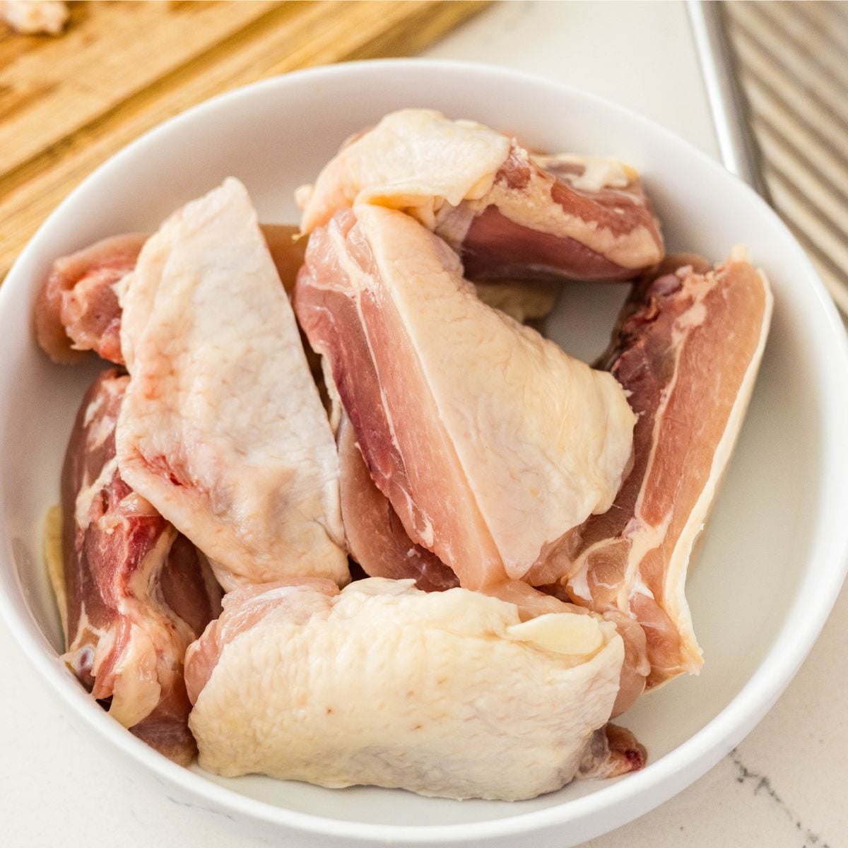 Raw bone-in chicken thighs in a white bowl