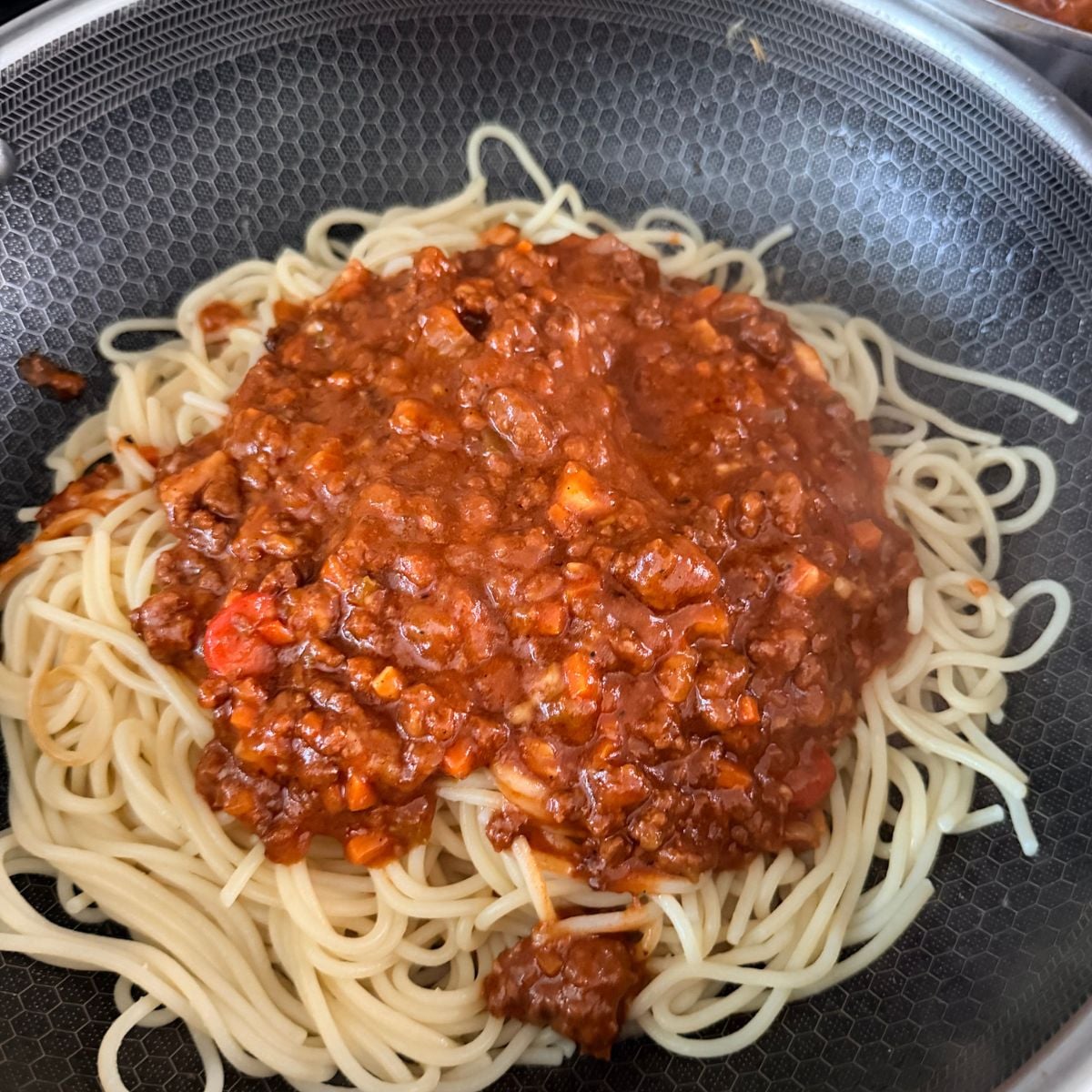 Filipino-style spaghetti topped with meat sauce and shredded cheese