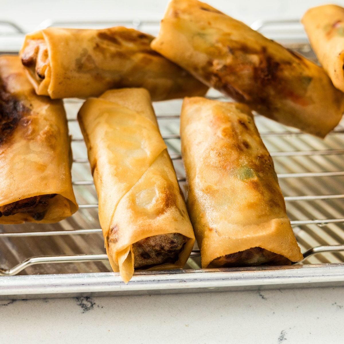 Golden fried lumpiang gulay draining on a wire rack