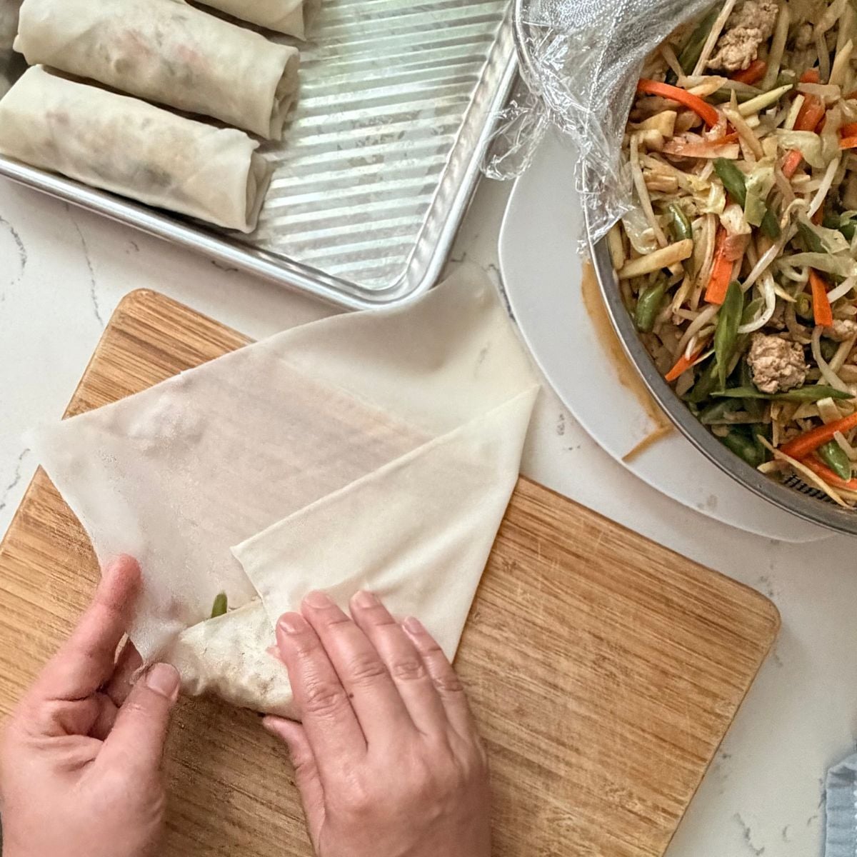 Folding the sides of a lumpiang gulay wrapper over the filling