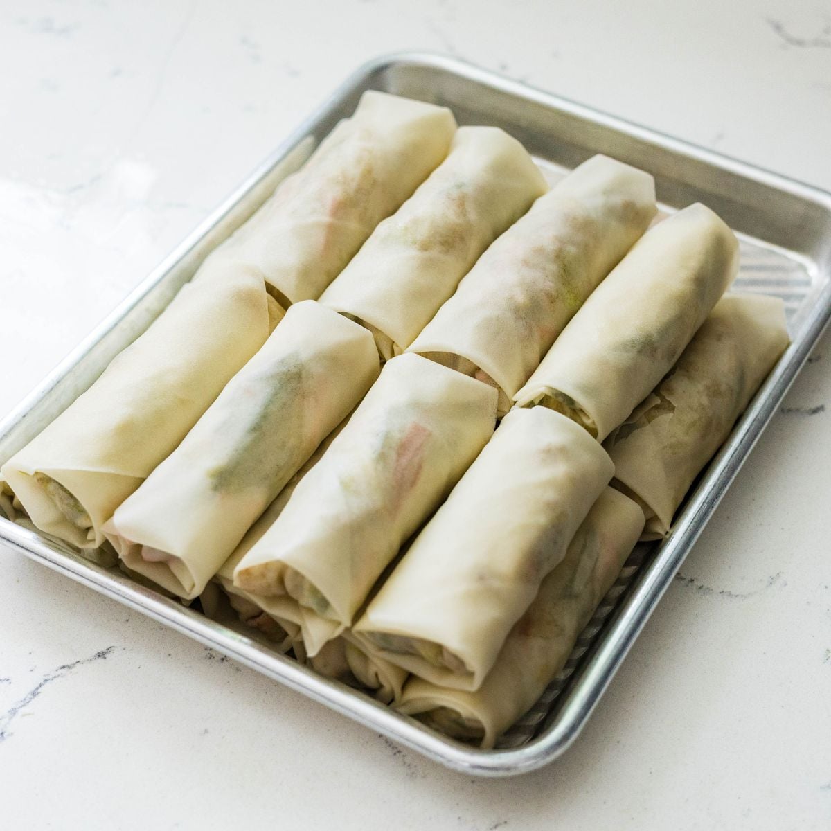 Uncooked lumpiang gulay arranged on a tray ready to freeze