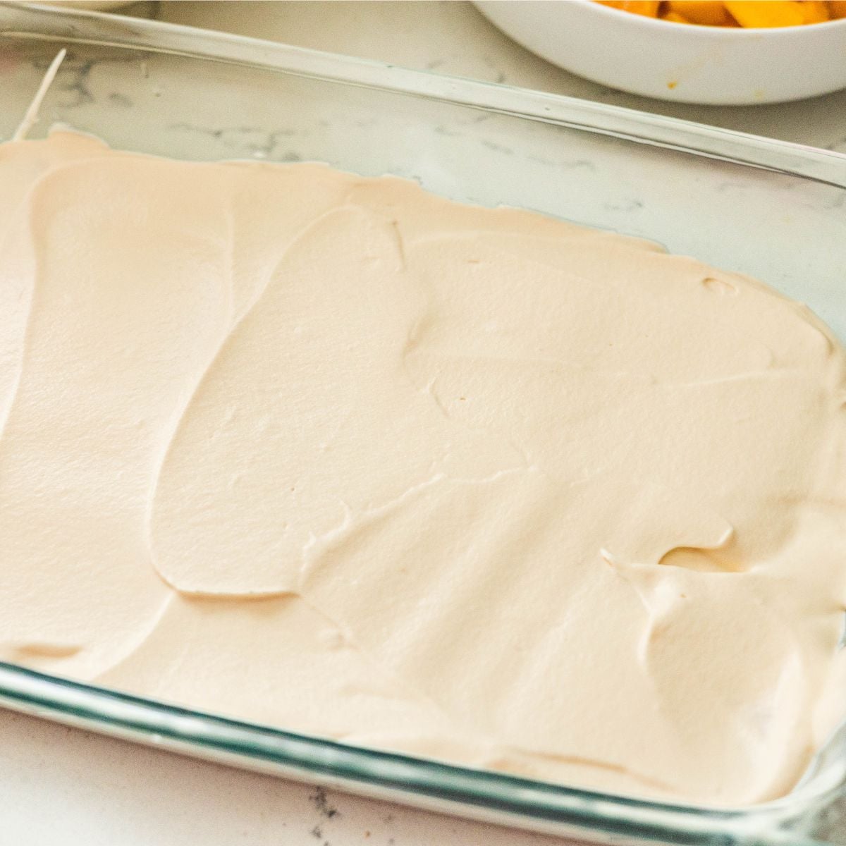 Cream mixture spread over graham crackers for mango float