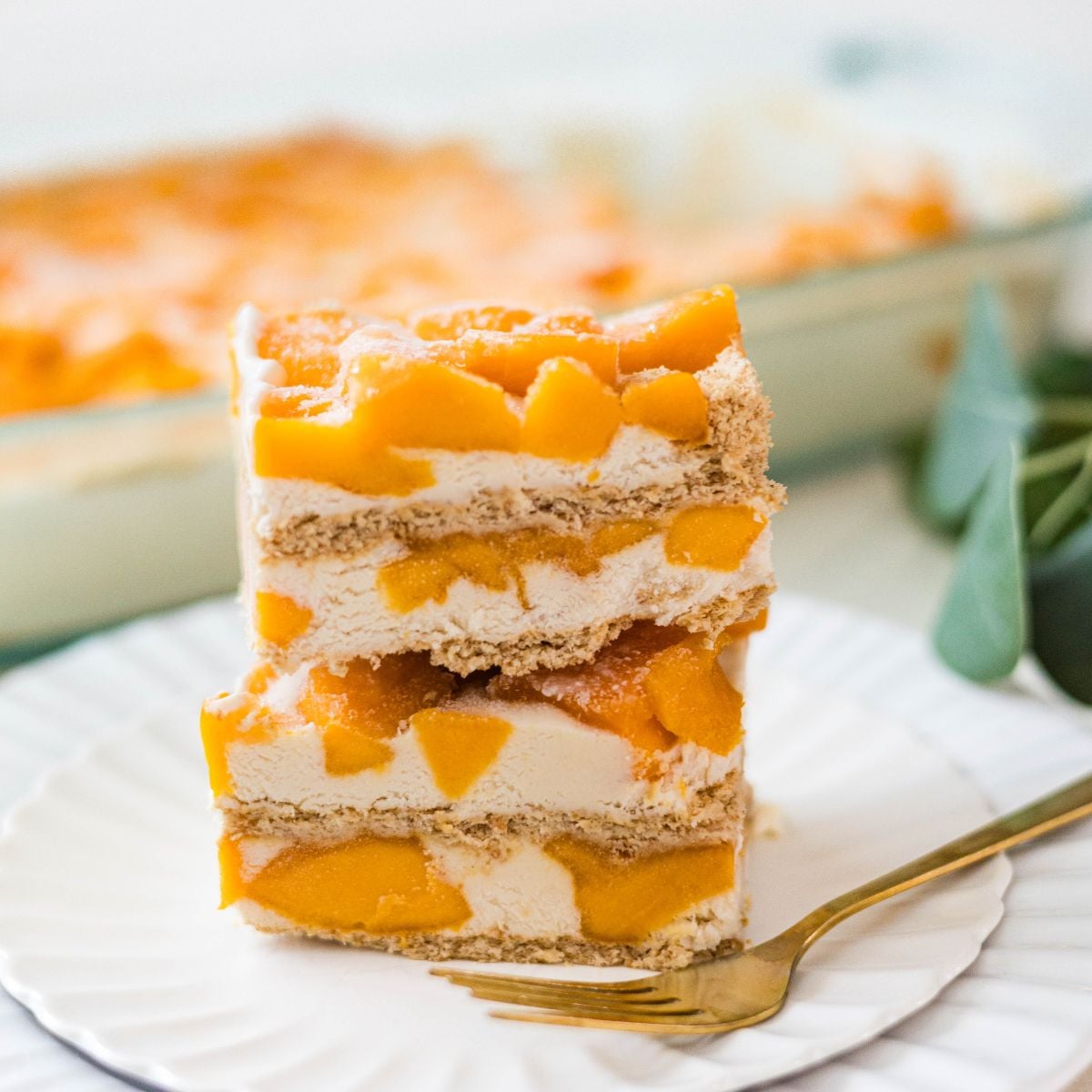 Stacked slices of creamy mango float with graham crackers and fresh mango